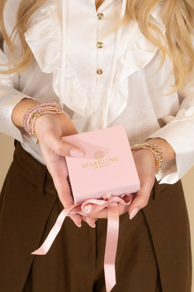Een delicate roze geschenkenbox met gouden letters en een bijpassende satijnen lintstrik.