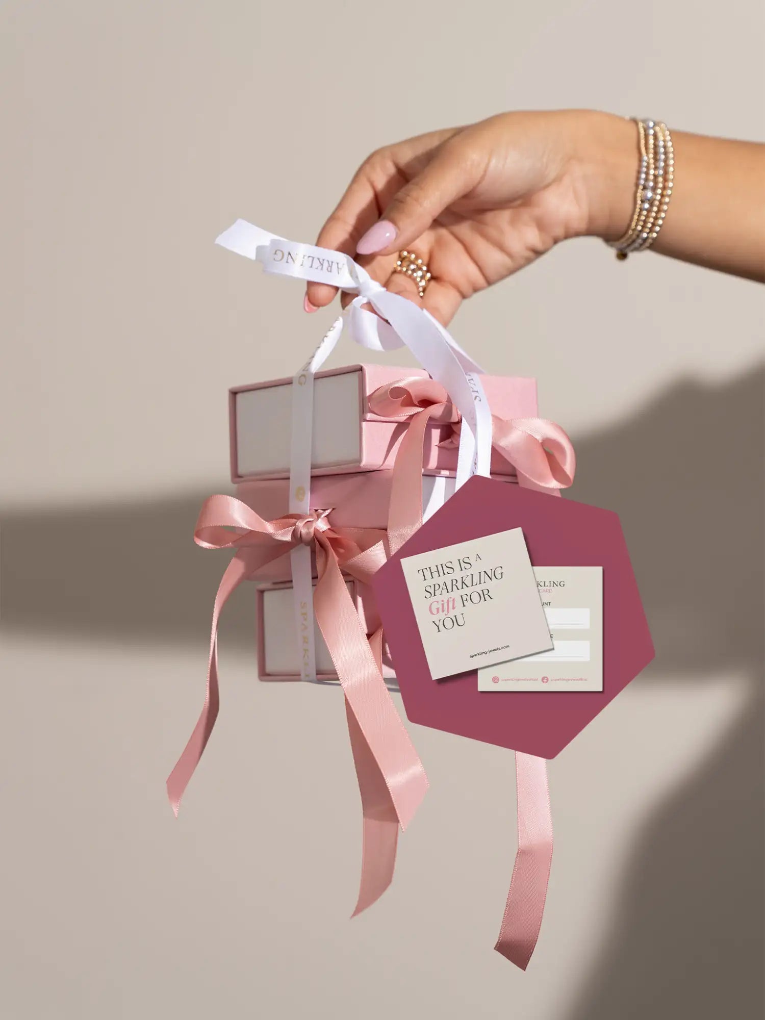 Een delicate roze satijnen lint dat in een strik is gebonden om een stapel bijpassende blush-roze cadeauverpakkingen.