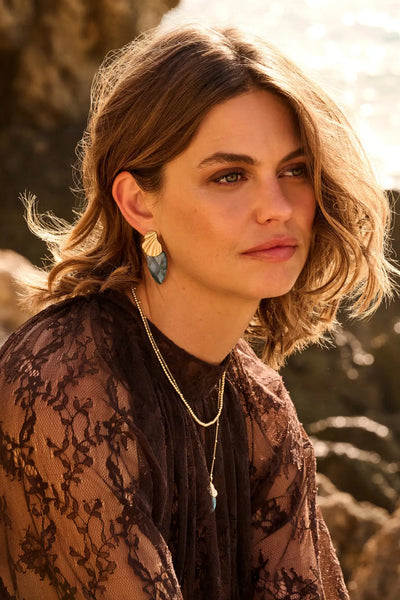 Goudkleurige, blad-vormige oorbellen met een donkergroen-blauwe steenaccent.