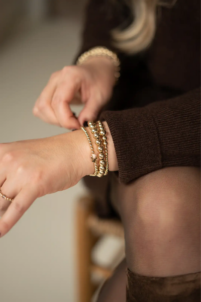 Goudkleurige kralenarmband met een centrale parelaccent.