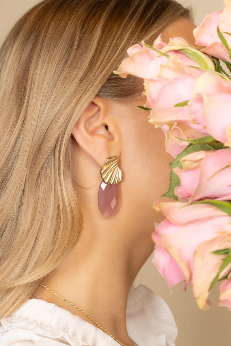 Goudkleurige schelpvormige oorbel met een hangend lavendel edelsteen hangertje