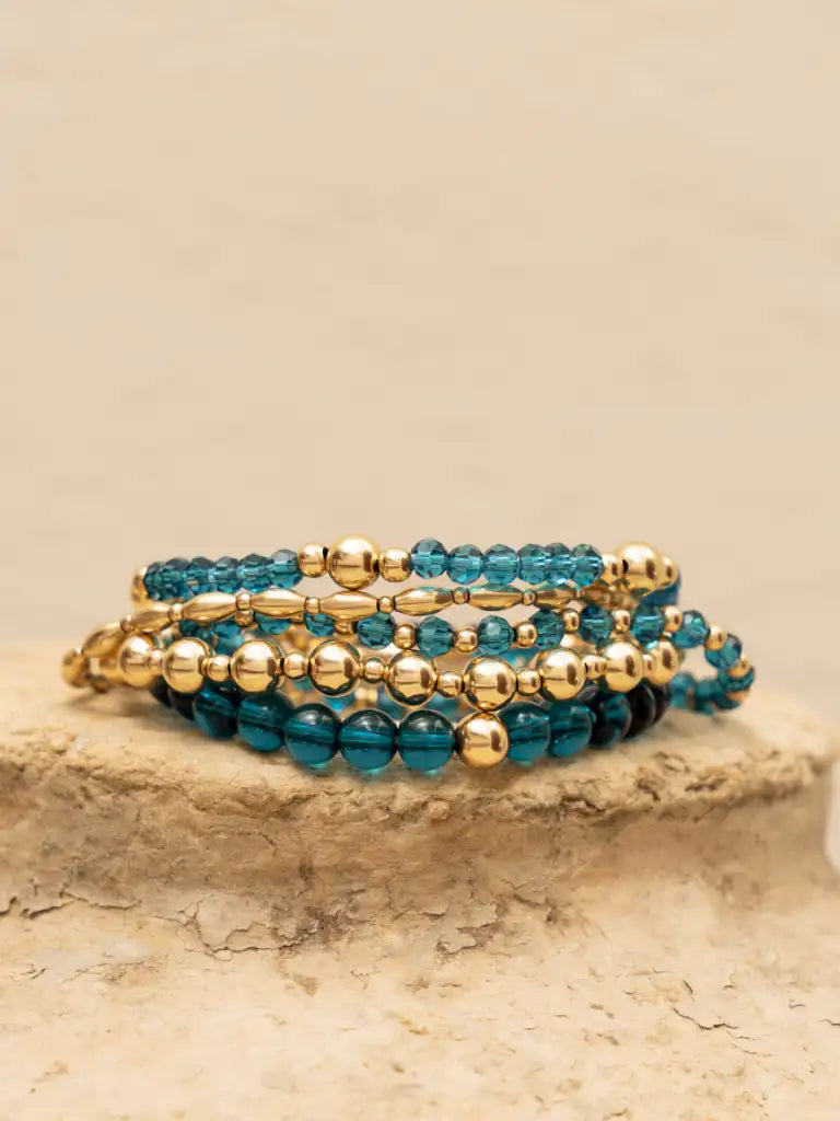 Een stapel elegante bewerkte wrap-armbanden met afwisselend turkoois en goudkleurige kralen in een mix van ronde en langgerekte vormen.