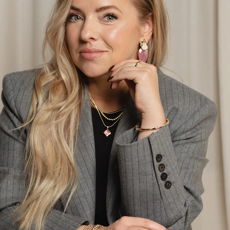 Een vrouw die een grijze pinstripe blazer met zwarte knopen draagt.