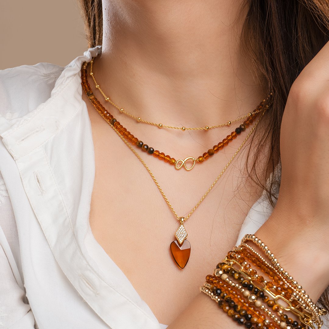 Oranje citrine quartz dames sieraden gedragen om hals en pols gecombineerd gouden kralen en Tijgeroog