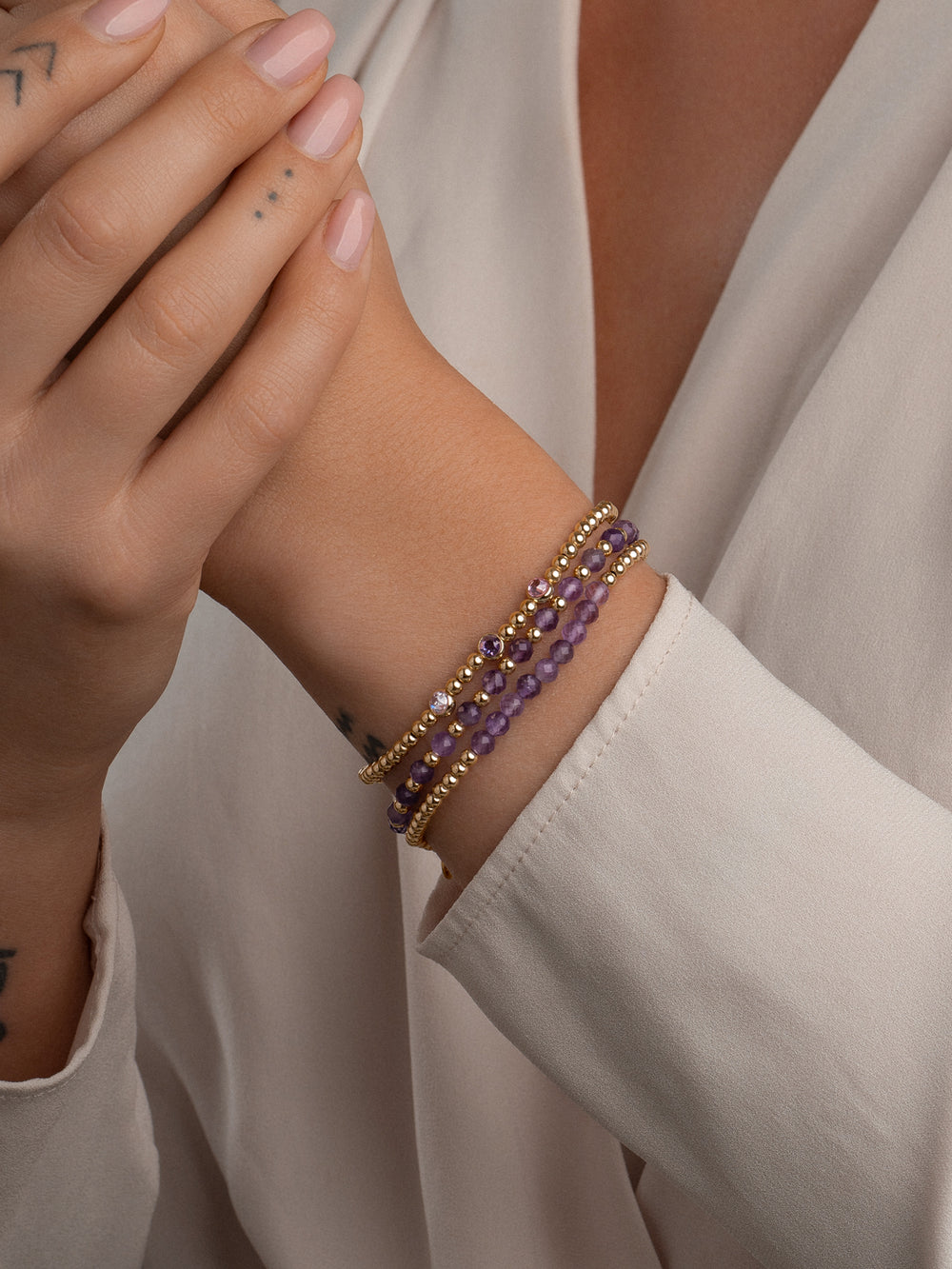 Goudkleurige elegantie: Ga voor een chique en trendy look met deze armbanden stack, waaronder de Amethyst Interstellar armband gemaakt van zilver en amethist kralen in een prachtige goudkleurige afwerking. Perfect om jouw outfit compleet te maken! #kleur_