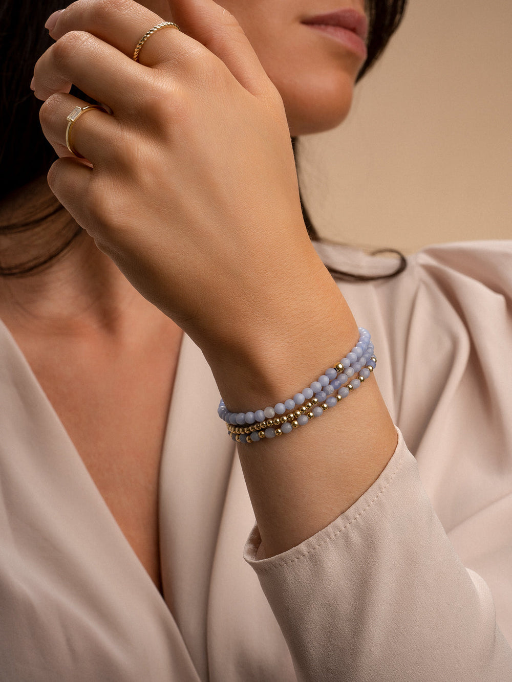 Dames hand met blauwe armbanden gouden kralen armband en blue lace agate kralen armband #kleur_goud
